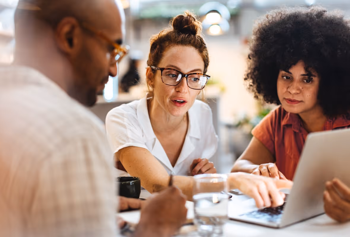 Twee vrouwen en een man discussiëren aan een tafel