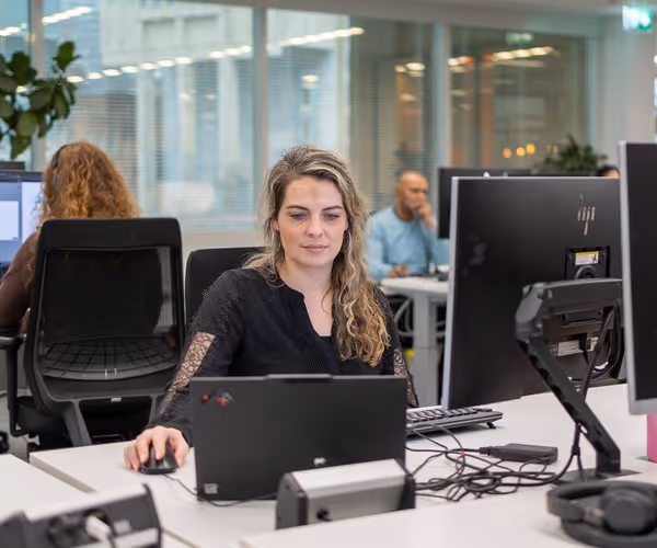 Een klantenservicemedewerker zit achter de computer om een klant te helpen