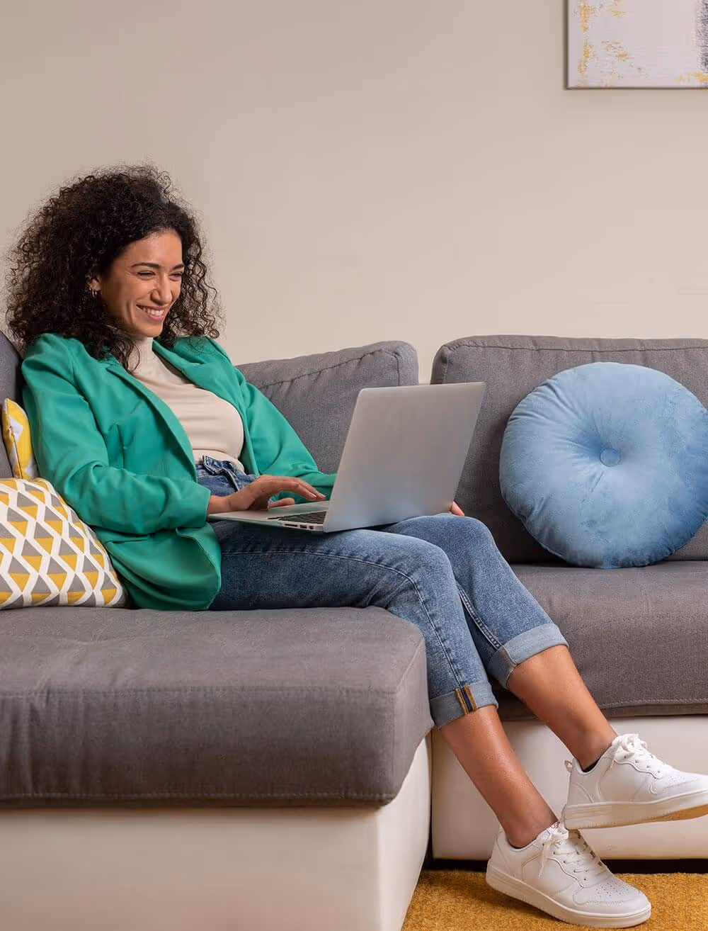 Lachende vrouw zit op de bank met laptop