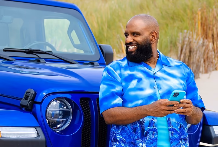 Willie zit in een blauwe auto met een groen surfboard erop en wijst naar links