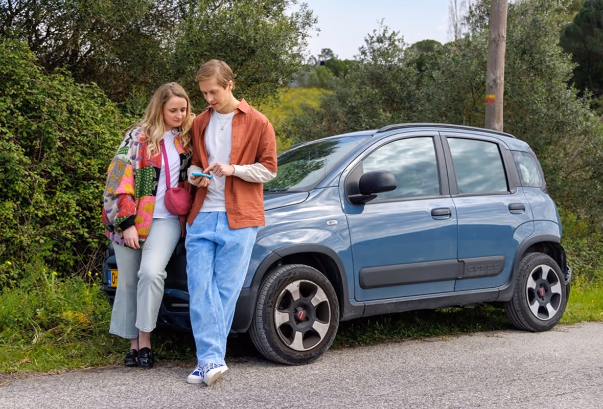 Stel kijkt op telefoon naast auto met pech