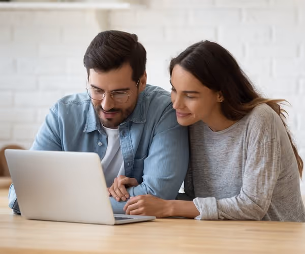 Een stel zit lachend samen achter de laptop