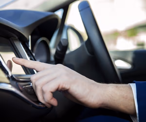 Een hand toetst iets in op een touchscreen in de auto